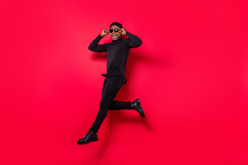 Fototapeta na wymiar Full length body size view of handsome trendy cheerful guy jumping running touching specs isolated over bright red color background