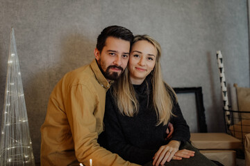 A young couple visibly in love offer each other moments of tenderness in a Christmas decoration with lights and ornaments