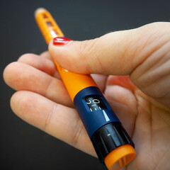 diabetic insulin. a pen with short-acting insulin lies in the hand on a dark background. side view...