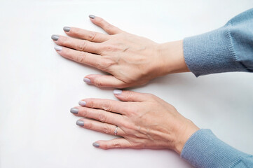 The hands of an adult 50s middle aged woman. Small wrinkles and swollen veins are visible. Beautiful neat manicure.