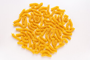 gluten-free spiral pasta fusilli, bright yellow, made from cornmeal, in an even layer on light...
