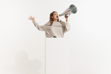 A young beautiful energetic caucasian woman announcing by megaphone hot news isolated on white...