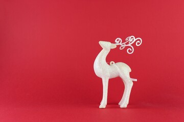 New Year's toy white deer on a red monochromatic background close-up. 