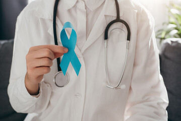Close up of professional female doctor in uniform and stethoscope holding light blue ribbon awareness. Men's health and Prostate cancer awareness campaign in November month. Symbol of medical issues