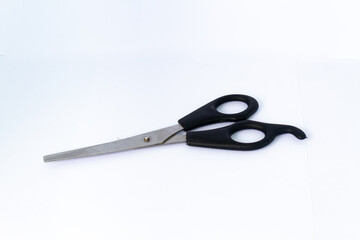 One pair of scissors with a black handle. Used for haircuts. Isolated on white background