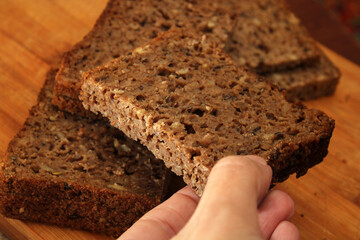 Woman's hand taking whole grain bread, close-up. Defocus. Healthy food concept.