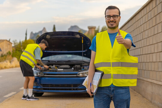 T&eacute;cnicos dando asistencia al autom&oacute;vil con aver&iacute;a, en la carretera.