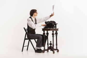 Handsome young hipster businessman thinking and writing with vintage typewriter. Old fashion style. - Powered by Adobe