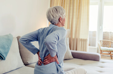 Woman feels back pain, massaging aching muscles. Mature woman feeling morning discomfort in aching...