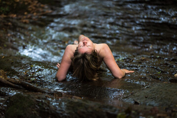 Naked 30 yo white woman resting on her arms in the water of the River Kyll, Kordel