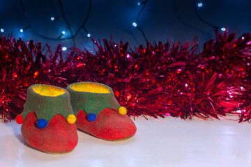 A pair of hand-crafted magical elf shoes full of Christmas light with a backdrop red tinsel and...