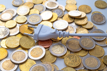 White electric plug, placed on a background of Euro coins. Increase in electricity bills, increases in electricity and energy costs.
