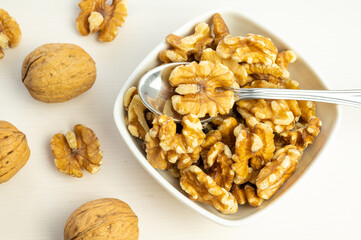 Walnuts in shell next to bowl containing shelled walnuts. Pruduction and consumption of nuts. Nutrition and properties of walnuts.
