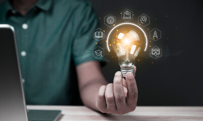 Businessman holding glowing lightbulb with learning icons for study knowledge to creative thinking idea and problem solving solution concept.