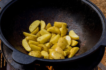 There is kazan cauldron on fire in nature where potatoes are frying