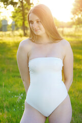 Beautiful young woman wearing white swimsuit strapless in nature on a summer day with backlight