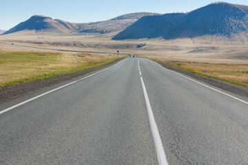 An asphalt road runs through the steppe. Autumn. Hills are visible in the distance