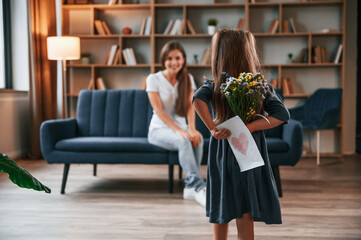 Happy mother's day. Giving a gift. Young woman with her daughter is together at apartment