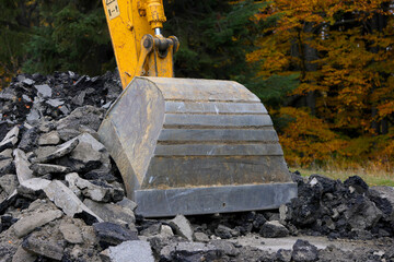Detail view of a big excavator used to destroy old asphalt road on a mountain road in autumn...
