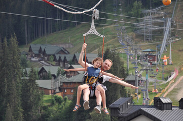 Happy father with his daughter is on the ski lift having fun and smiling. Majestic view of Carpathians