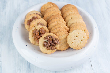 Different cookies in a plate on a light wooden table.