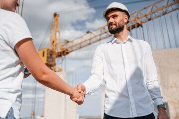 Naklejka na ściany i meble Doing handshake. Successful agreement. Man in uniform working with woman on the construction site