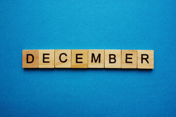 The word December is made of wooden cubes. The name of the months. Winter months. Copy space. Blue background