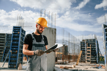 Control of the process. Foreman is with documents. Man in uniform is working on the construction...