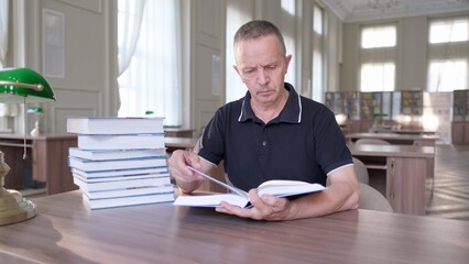 Portrait of caucasian Senior man working with book in public library. Adult student at the library,...