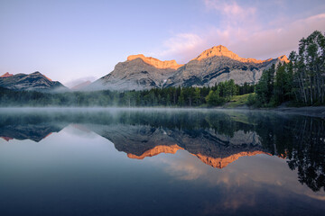 Sun hitting the mountain peaks as the sun rises at Wedge Pond, Canadian Rockies