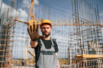 Closed area. Stop gesture. Man in uniform is working on the construction site