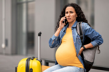 Unhappy pregnant woman travelling alone, having phone conversation