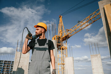 Portrait of man that is in uniform with the drill on the construction site