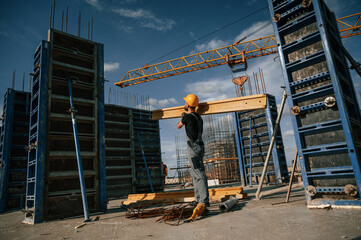 Fototapeta premium Yellow colored wooden plank. Man in uniform is working on the construction site