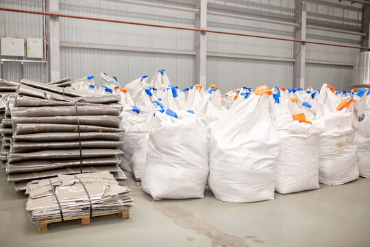 A number of rolls of aluminum lies in the production shop of the plant. Metal processing, aluminum plant. Bags with recycled raw materials are recycled.