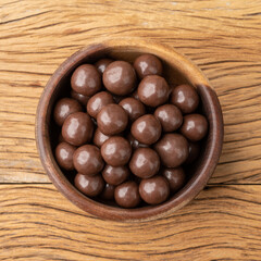 Chocolate malted balls in a bowl over wooden table