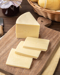 Artisanal Alagoa cheese from Minas Gerais, Brazil over a wooden board with bread and jam