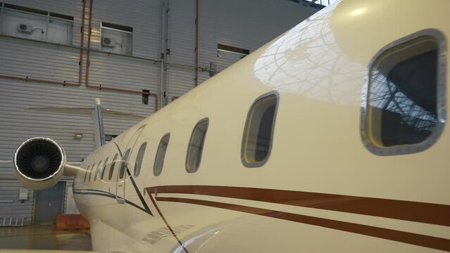 Close Shot of a Brand New Airplane board Standing in a Aircraft Maintenance Hangar. Business plane jet on parking. High quality FullHD footage