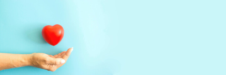 female hand heart on a blue background, banner, right copyspace. Women's health is under protection, a woman's love. Heart research medical. Cardiology practice.