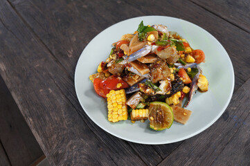 Papaya salad with blue crab and corn in a plate placed on a wooden table