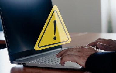 Businessman using computer laptop with triangle caution warning sing for notification error and maintenance concept