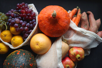 Various healthy autumnal food in reusable mesh bags. Top view, dark background.