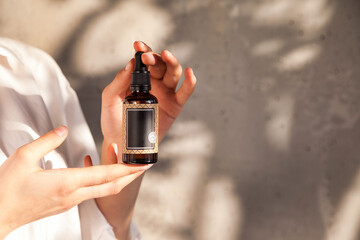 Close up woman hands holding massage or cosmetics oil bottle for applying drops to skin or hair....