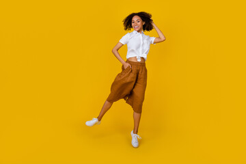 Fototapeta na wymiar Full size portrait of charming cheerful carefree girl jumping hand touch hair isolated on yellow color background