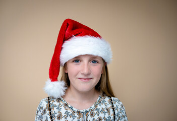 young girl with santclaus hat and gifts in front of brown background