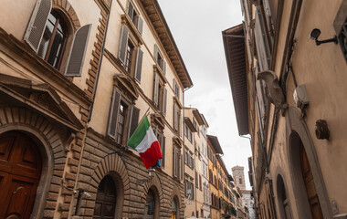 Beautiful narrow historic street with vintage houses with Italian flag in Florence, Italy. Traveling in European city. Holidays