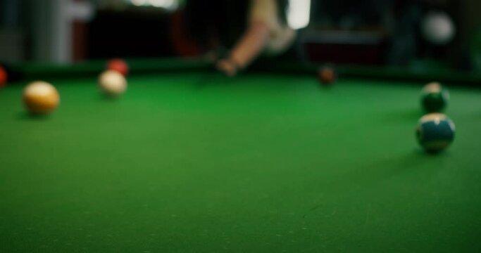 Sinking yellow ball number one into a pocket.Sports game of billiards on a green cloth. Billiard balls with numbers on a pool table. Billiards team sport.