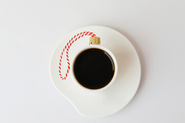 Cup of black espresso coffee decorated as Christmas tree ball on an elegant saucer. White background. New Year concept