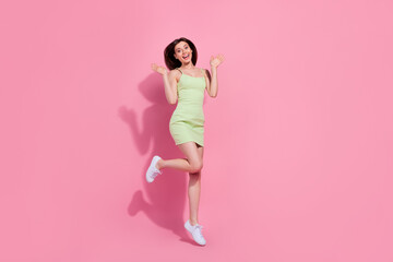Fototapeta na wymiar Full length photo of excited impressed girl dressed green outfit jumping high empty space isolated pink color background