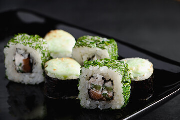 Set of sushi rolls on black plate. Uramaki and futomaki rolls